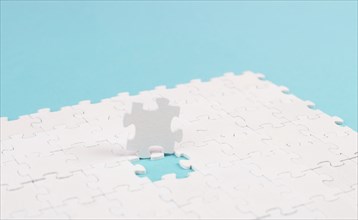 White jigsaw on a blue background, missing parts, working together as a team, searching for