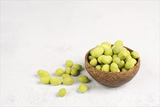 Pile of green wasabi coated peanuts in a bowl, spicy snack, oriental food