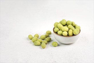 Pile of green wasabi coated peanuts in a bowl, spicy snack, oriental food