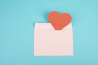 Pink envelope with a red heart, empty copy space, blue background, valintines day greeting card,