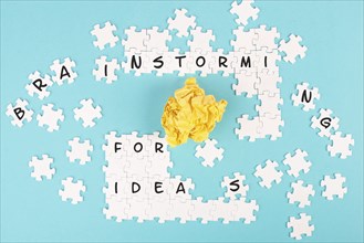 Puzzle on a blue background, yellow crumpled paper, words brainstorming for ideas are standing on