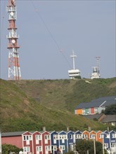 Colourful rows of houses in front of a green hill with a transmission mast and a radio station,