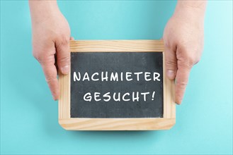 Holding a chalkboard in the hands, looking for a new tenant is standing in german language on the