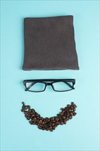 Human face made with a wool hat, glasses and coffee beans as a beard, funny minimalist portrait,