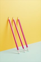 Pink pencils on a yellow and blue background, minimalism, creative, surreal and education concept,