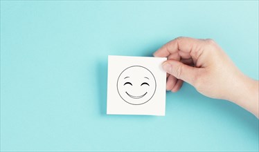 Smiling happy face on a paper, positive emotions, good customer feedback, laughing, blue background