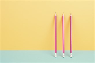 Pink pencils on a yellow and blue background, minimalism, creative, surreal and education concept,