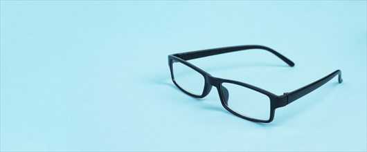 Glasses with a black frame on a blue background, copy space for text