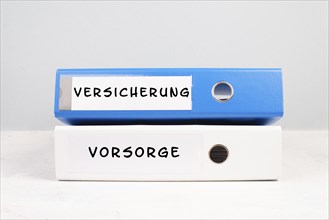 Two folders with the words insurance and precaution in german langauge, documents at an office,