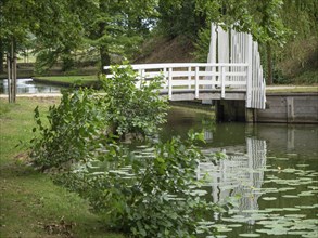 White bridge over a quiet river, surrounded by green nature and plants in the park, groenlo,