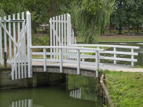 White wooden bridge over a quiet river, surrounded by trees and nature, groenlo, gelderland, the