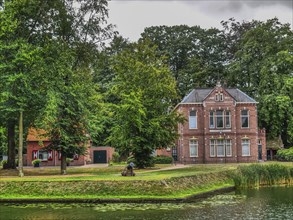 Large brick villa in a park with pond, surrounded by trees and green grass, groenlo, gelderland,