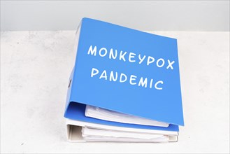 The words monkeypox pandemic are standing in german language on a folder, outbreak of the MPXV