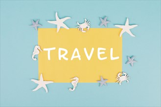 The word travel is standing on a yellow colored paper, sea stars, seahorses and crab bulding a