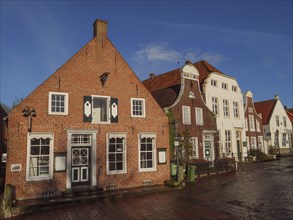 Brick houses along a damp cobbled street on a sunny day, greetsiel, east frisia, germany