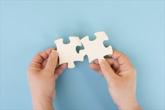 Holding two pieces of a puzzle in the hands, connecting together as a team, solving a problem,