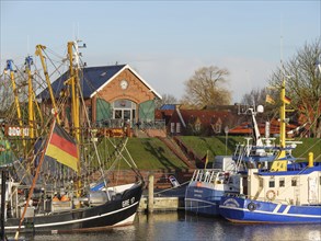 Fishing boats and colourful flags in the harbour, behind reddish houses under a clear sky,