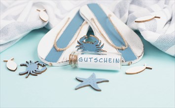 Blue colored summer and vacation background, flip flops, sea stars and a glass bootle with the word