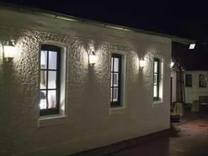 House with large windows and wall lamps that create a peaceful and quiet night atmosphere,