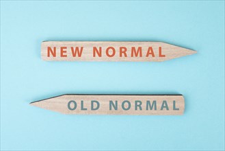 The words new and old normal are standing on wooden arrows, transformation of society after