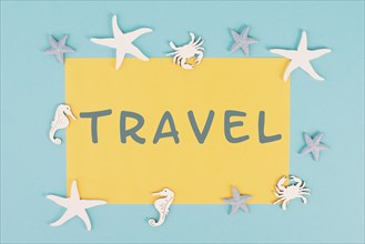 The word travel is standing on a yellow colored paper, sea stars, seahorses and crab bulding a