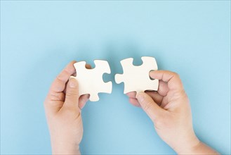 Holding two pieces of a puzzle in the hands, connecting together as a team, solving a problem,