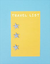 Travel list is standing on the yellow colored paper, sea stars, holiday plan and destination,