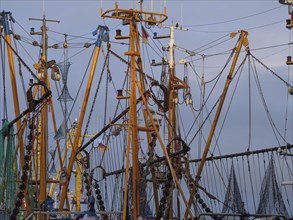 Detailed view of fishing boats and masts in the harbour, many cables and orange colours dominate,