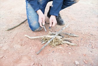 Starting a fire with a firesteel, survival and adventure equipment, outdoor skill, man making a