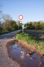 Path in the countryside, warning sign for cars, no enty, puddle after the rain, landscape in