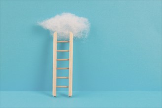 Ladder with a cloud on top, blue colored background, copy space, dreaming of success, creative and