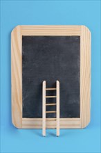 Ladder on an empty chalkboard, blue colored background, copy space, education, success, creative