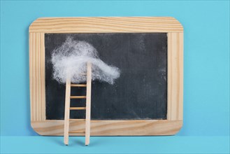 Ladder with a cloud on top, blank chalkboard, blue colored background, copy space, dreaming of