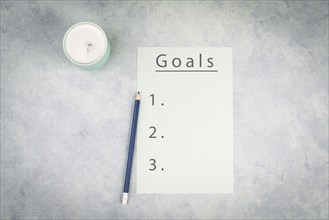 Empty paper with a pen on a textured background, the word goal is standing on the top of the page,