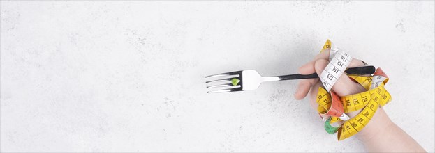 One single pea on a fork, hand with tape measure and fork, diet and loosing weight concept, healthy