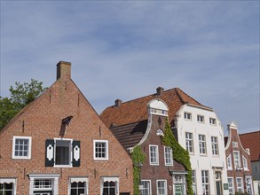 Historic brick houses with gabled roofs and plastered facades under a clear sky, greetsiel, east