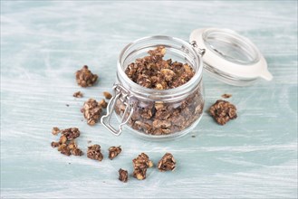 Muesli with chocolate in a glass on a turquoise blue and white shabby background, empty space for