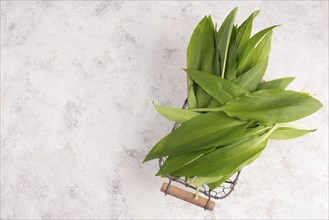 Pesto made from wild garlic, pine nuts and feta cheese in a glass, with fresh leaves on a textured