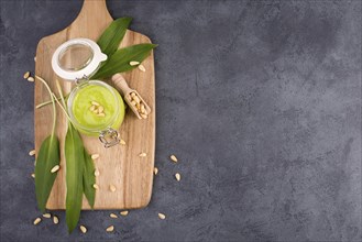 Pesto made from wild garlic, pine nuts and feta cheese in a glass, with fresh leaves on a dark