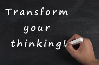 The phrase transform your thinking is standing on a chalkboard, change the mindset, strategy and