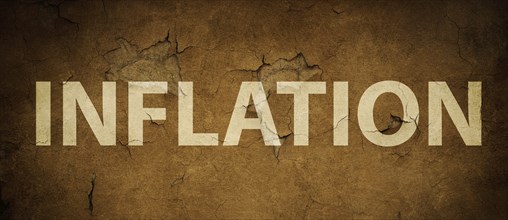 The word inflation is standing on a brown textured wall, increasing living costs