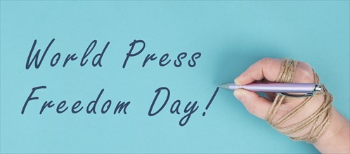 World Press Freedom Day is standing on a paper, hand with pen is chained, free speech, cancel