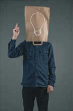 Young man with a paper bag on his head, light bulb, having an idea, start up