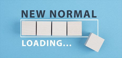 The words new normal are standing on wooden cubes, loading bar, blue colored background