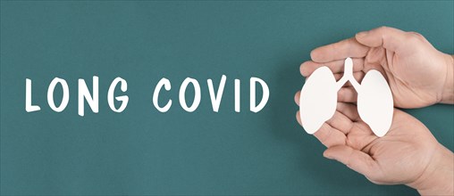 The words long covid are standing on a paper, hands hold a lung, breathing problems after Covid-19