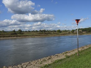 River and riverbank with posts under cloudy sky, Doesburg, Gelderland, Netherlands