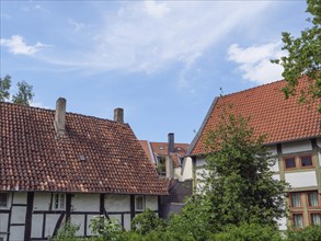 Red-tiled roofs of half-timbered houses under a partly cloudy sky with green vegetation, Detmold,