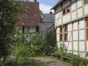 Half-timbered houses with lush garden and green bench, creating a cosy and traditional atmosphere,