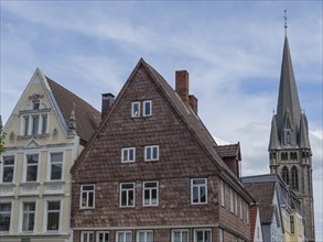 Church with high tower, surrounded by traditional half-timbered houses and cloudy sky, Detmold,