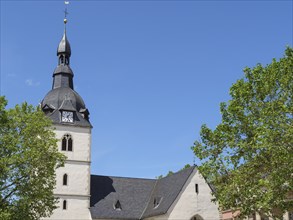 Church tower and main building of a church surrounded by trees under a clear sky, Detmold, North